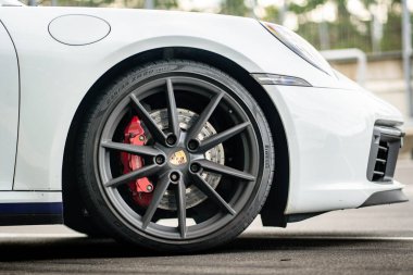 Brno, Czech Republic - October 24, 2025: Detail of the front wheel of a Porsche 911 sports car. White fast car parked outdoors.