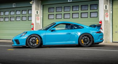 Brno, Czech Republic - October 24, 2025: Blue Porsche 911, fast sports car stands outside at the garage on the racing circuit.