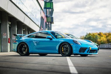 Brno, Czech Republic - October 24, 2025: Blue Porsche 911, fast sports car stands outside at the garage on the racing circuit.