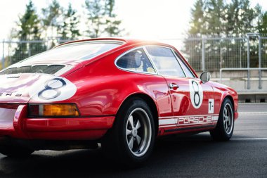 Brno, Czech Republic - October 24, 2025: Old historic Porsche 911 racing car in red color parked outdoors on a racing circuit. View of the fast car from the back.