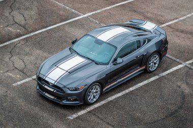 Brno, Çek Cumhuriyeti - 31 Aralık 2023: Gri Amerikan spor otomobili Ford Mustang açık otoparkta duruyor. Beyaz çizgili araba, folyo etiketli. Hızlı araba üst görünümü.