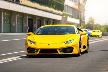Brno, Çek Cumhuriyeti - 10 Ekim 2025: Sarı İtalyan spor otomobili Lamborghini Huracan yarış pistinin kenarından geçiyor. Maden ocağının önünde süper spor araba.