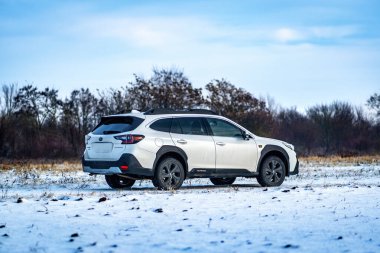 Brno, Çek Cumhuriyeti - 20 Ocak 2025: Beyaz Subaru Outback aile arabası açık havada bir çayırda. Japon cipi kışın kırsalda karda.