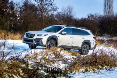 Brno, Çek Cumhuriyeti - 20 Ocak 2025: Beyaz Subaru Outback aile arabası açık havada bir çayırda. Japon cipi kışın kırsalda karda.