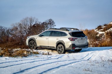 Brno, Çek Cumhuriyeti - 20 Ocak 2025: Beyaz Subaru Outback aile arabası açık havada bir çayırda. Japon cipi kışın kırsalda karda.