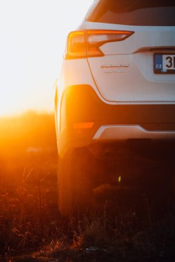 Brno, Çek Cumhuriyeti - 10 Şubat 2026: Sunlit Subaru Outback, açık bir çayırda. Japon arazi aracı beyaz renkli ve turuncu güneş batıyor..