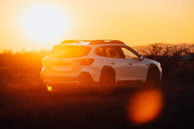 Brno, Çek Cumhuriyeti - 10 Şubat 2026: Japon off-road otomobili Subaru Outback doğada kışın gün batımında bir arazide duruyor. Yolculukta beyaz bir SUV 'a radyasyon.