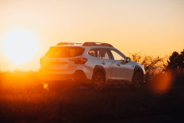 Brno, Çek Cumhuriyeti - 10 Şubat 2026: Japon off-road otomobili Subaru Outback doğada kışın gün batımında bir arazide duruyor. Yolculukta beyaz bir SUV 'a radyasyon.