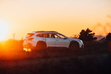 Brno, Çek Cumhuriyeti - 10 Şubat 2026: Japon off-road otomobili Subaru Outback doğada kışın gün batımında bir arazide duruyor. Yolculukta beyaz bir SUV 'a radyasyon.