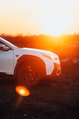 Brno, Çek Cumhuriyeti - 10 Şubat 2026: Sunlit Subaru Outback, açık bir çayırda. Japon arazi aracı beyaz renkli ve turuncu güneş batıyor..