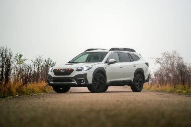 Brno, Çek Cumhuriyeti - 12 Kasım 2025: Beyaz aile arabası Subaru Outback sonbaharda sisli havada doğada yolda. Japon arazi aracı..