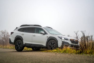 Brno, Çek Cumhuriyeti - 12 Kasım 2025: Beyaz Subaru Outback aile arabası sonbaharda siste bir yerden diğerine gidiyor. Japon arazi aracı..