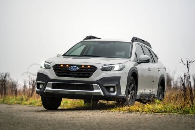 Brno, Çek Cumhuriyeti - 12 Kasım 2025: Beyaz Subaru Outback aile arabası sonbaharda siste bir yerden diğerine gidiyor. Japon arazi aracı..