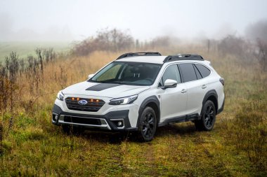 Brno, Çek Cumhuriyeti - 12 Kasım 2025: Beyaz Subaru Outback aile arabası sonbaharda bir arazide siste duruyor. Japon üretimi off-road SUV doğada.