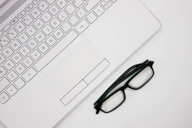 Evde çalışırken dizüstü bilgisayar ve gözlüklerin üst görüntüsü. Ev ofisinde en az çalışma alanı