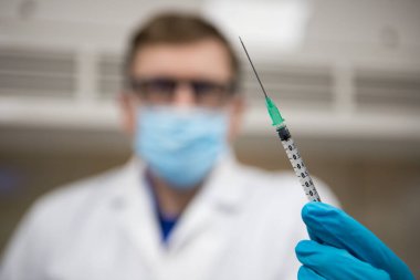 Coronavirus aşısı bağışıklık aşısı için hazır. Eldivenli doktor elinde hiperdermik iğne ve aşı dozuyla