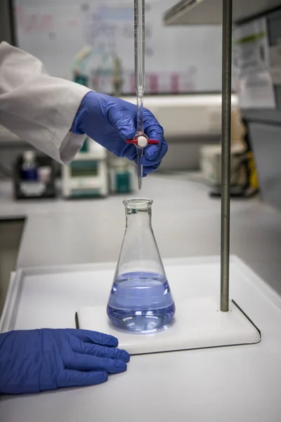 Chemik Rękawiczkami Laboratorium Analizującym Próbkę Przez Miareczkowanie — Zdjęcie stockowe