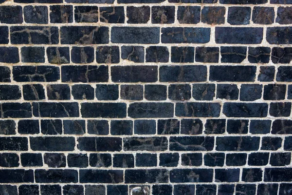 Dark, black Weathered brick wall made from reclaimed bricks. Black brick wall