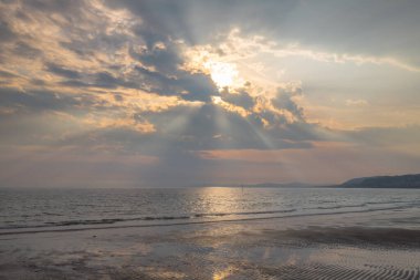 Colwyn Körfezi, Kuzey Galler 'in yukarısında dramatik bir gökyüzü. Sakin bir denizle sahilde şafak sökerken