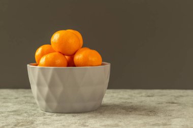 Taze organik narenciye mandalinası gri taşlı arka planda gri bir kasede meyve verir. Seçici odak, kenar görünüm ve boşluk kopyala