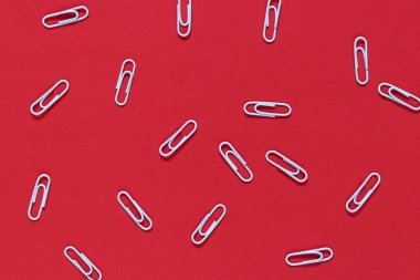 Beyaz metal ataçlar kırmızı arka plana rastgele saçılmış. İş konsepti. Konsept çalış.