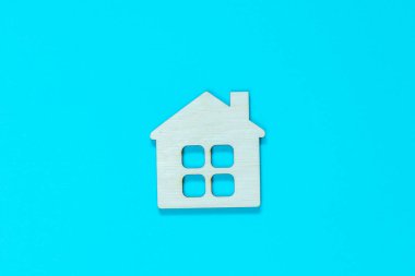 Mavi arka planda ahşap bir evin heykeli. Gayrimenkul, ev satın alma ve satış kavramı. Düşük fiyata uygun konutlar. Aile için eve. Ev konseptinde kal.