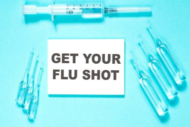 Grip aşını ol. Mavi arkaplan üzerinde beyaz kağıt üzerinde metin ampul ve şırınga, yakın plan