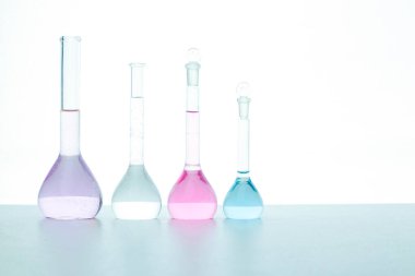 Beyaz arka planda renkli reaksiyonlu şeffaf mataralar izole edildi. Tek sıra halinde düzenlendi. Seçici odaklanma. Tıp, bilim ve sağlık hizmetleri kavramı.