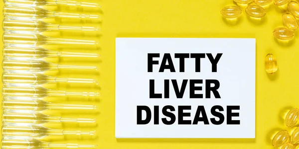 Notepad with text FATTY LIVER DISEASE closeup, capsules and ampoules. Medical and health care concept.
