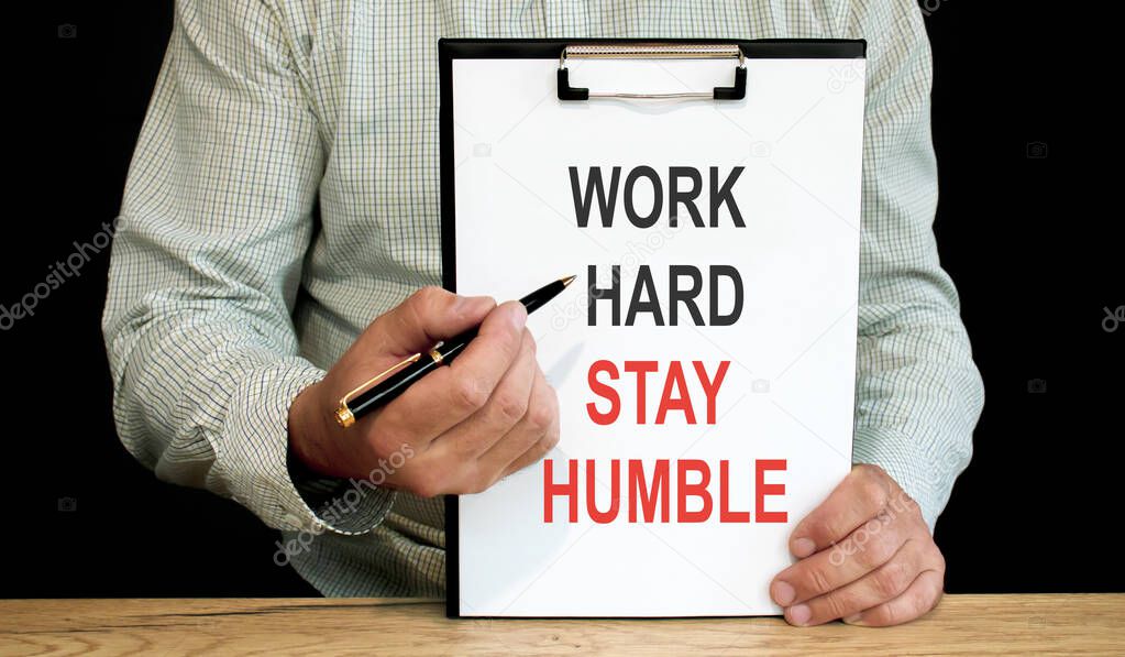 Work hard stay humble word inscription on white card paper sheet in hands of a businessman. recap concept. white paper
