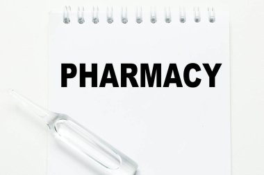 PHARMACY kelimesi beyaz arkaplan üzerinde ampulün yanındaki deftere yazılmıştır. Tıbbi konsept