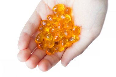 Eldeki ve beyaz arka plandaki sarı hapların üst görüntüsü. Elinde sarı haplar yığını var. Tıbbi ve sağlık hizmetleri kavramı.