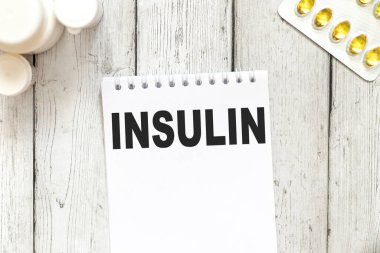 İnsülin - beyaz arkaplanda metin. Etrafta çeşitli haplar ve vitaminler var. Tıbbi ve sağlık hizmetleri kavramı