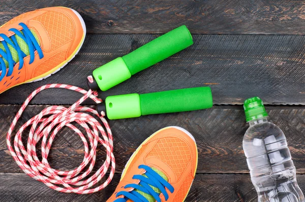 Zapatos deportivos, saltar la cuerda y la botella de agua en la madera vieja —  Fotos de Stock