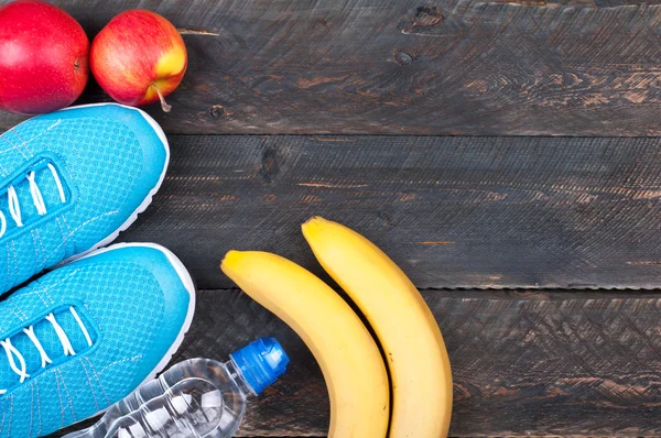 Sport och hälsosamt liv. Sport skor, äpplen, bananer och flaska Stockfoto