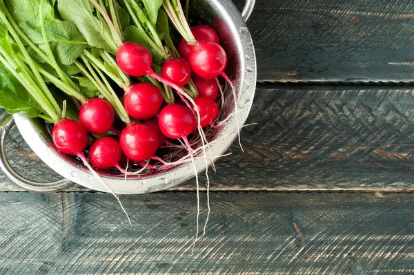 Radijs in een kom op een houten tafel. Lente groenten op een rusti — Stockfoto