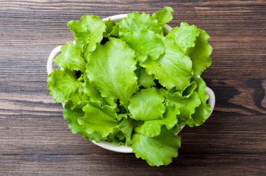 Ahşap rustik arka plan üzerinde bir kase taze marul. Yemek salatası