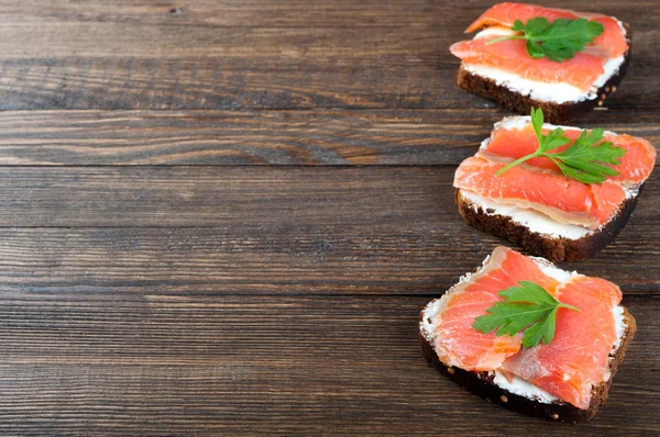 Smörgåsar med lax, smör och persilja på ett träbord. Hälsosam mat till frukost eller mellanmål. Mat bakgrund — Stockfoto