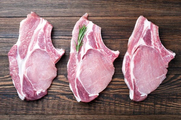 Filete de carne fresca cruda con romero de hierbas sobre fondo de madera. Carne de cerdo cruda —  Fotos de Stock