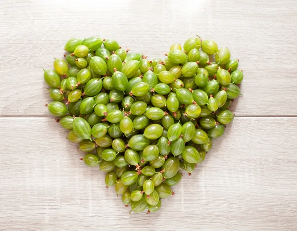 Зеленые ягоды на деревянном фоне. Сердце крыжовника летний ягод — стоковое фото