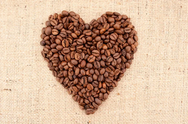 Chicchi di caffè a forma di cuore su sfondo iuta — Foto Stock