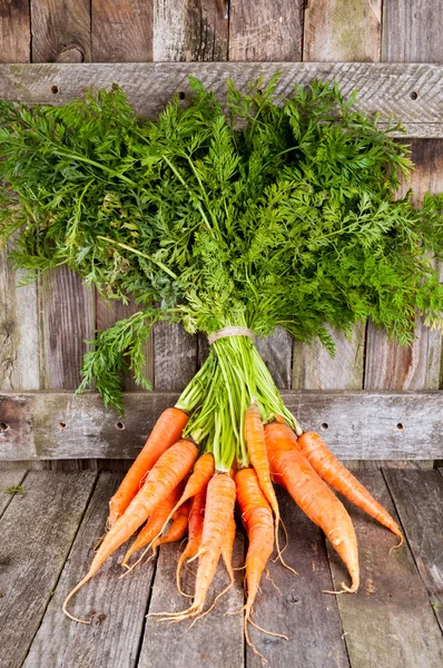 Grappolo di carote fresche su sfondo in legno rustico — Foto Stock