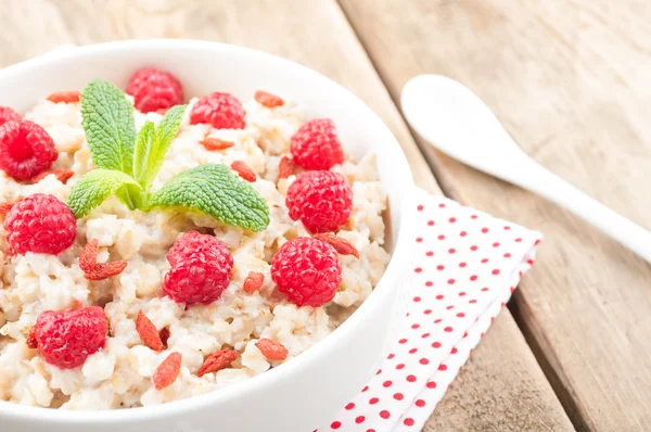 Havregrynsgröt i skål med hallon, Goji och myntablad. Bra frukost. Diet, detox och hälsosamt liv Concept — Stockfoto