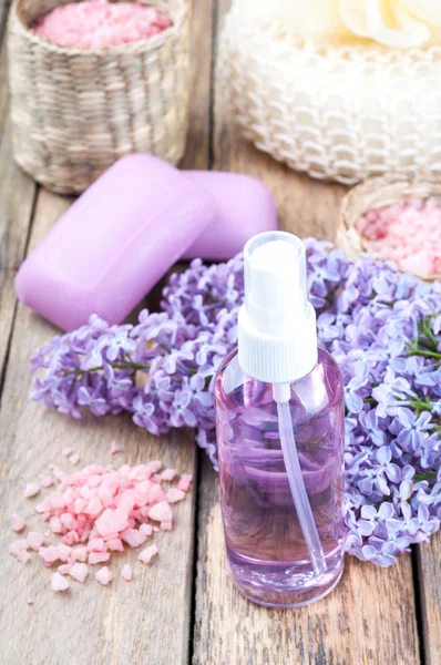 Fondo Spa con fiori lilla in fiore e bottiglia di olio essenziale o idrolato di fiori, sapone aromatico cosmetico e sale marino — Foto Stock