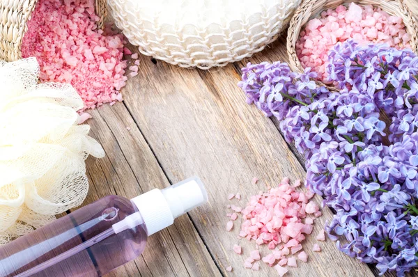 Fondo Spa con fiori lilla in fiore e bottiglia di olio aromatico o idrolato di fiori, sapone cosmetico, sale marino e accessori — Foto Stock