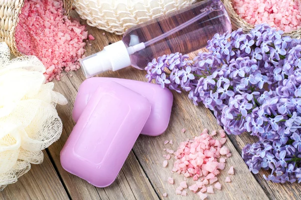 Spa achtergrond met bloeiende lila bloemen en fles aroma olie, cosmetische zeep, zeezout — Stockfoto