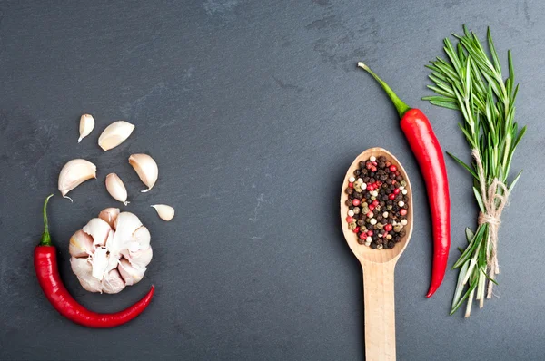 Rosmarino, pepe in un cucchiaio, peperoncino e aglio su fondo scuro. Spezie ed erbe sfondo con spazio copia — Foto Stock