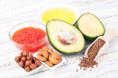 Gıdalar sağlıklı yağlar ile. Kaynakları omega 3 - avokado, zeytin yağı, kırmızı havyar, fındık ve ahşap arka plan üzerinde keten tohumu