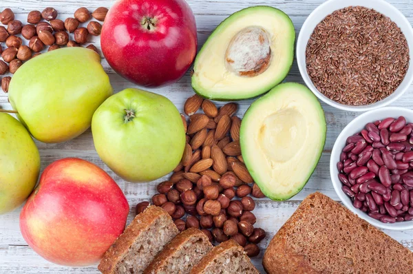 Cibo sano avokado, semi di lino, pane integrale, noci e mele su sfondo di legno — Foto Stock