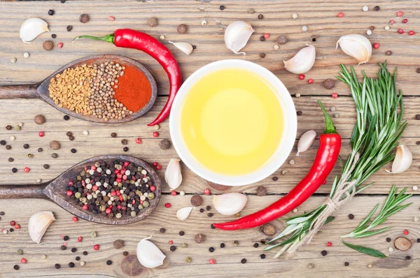 Fundo alimentar com azeite, alecrim, pimenta, páprica, feno-grego, coentro, pimenta e alho sobre mesa rústica de madeira. Fundo de especiarias — Fotografia de Stock